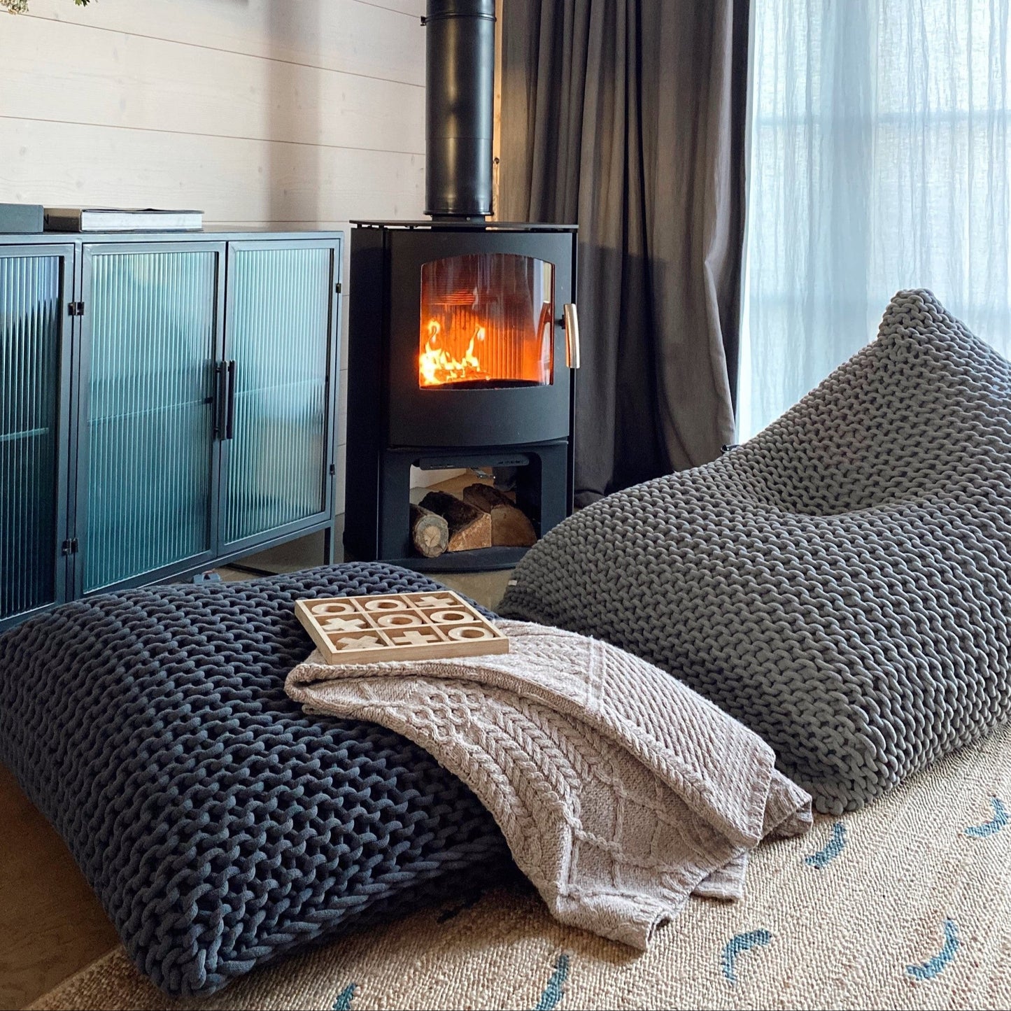 giant knitted bean bag and floor cushion chair in front of wood burner